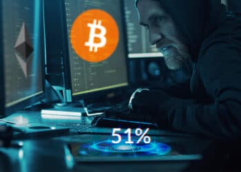 Hacker con dos pantallas, una bitcoin y otra ether y 51% sobre su teléfono.