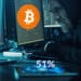 Hacker con dos pantallas, una bitcoin y otra ether y 51% sobre su teléfono.