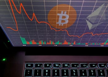 Bitcoin y ether en pantalla con gráfico rojo.