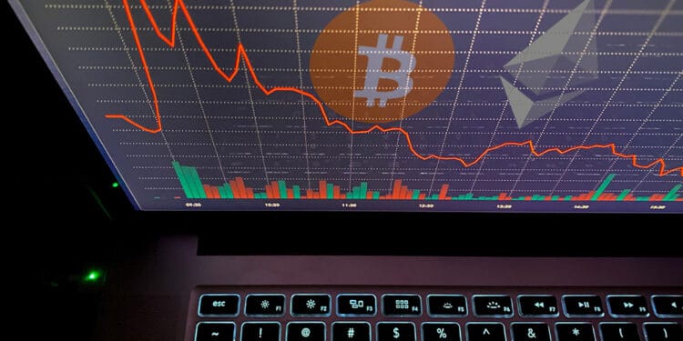Bitcoin y ether en pantalla con gráfico rojo.