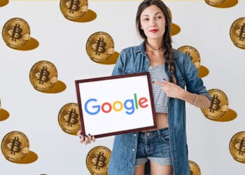 Persona sosteniendo cartel de Google con bitcoins en de fondo.