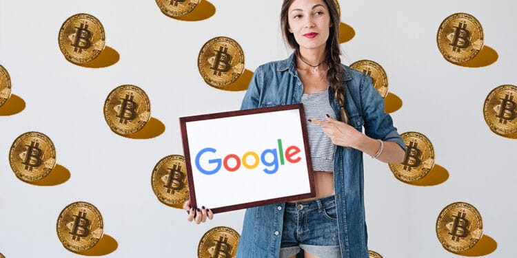 Persona sosteniendo cartel de Google con bitcoins en de fondo.