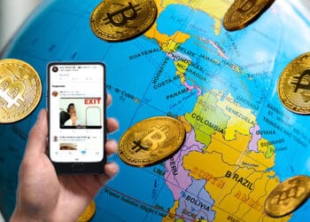 Globo terráqueo con énfasis de Suramerica, lluvia de bitcoins y mano sosteniendo teléfono con Twitter.