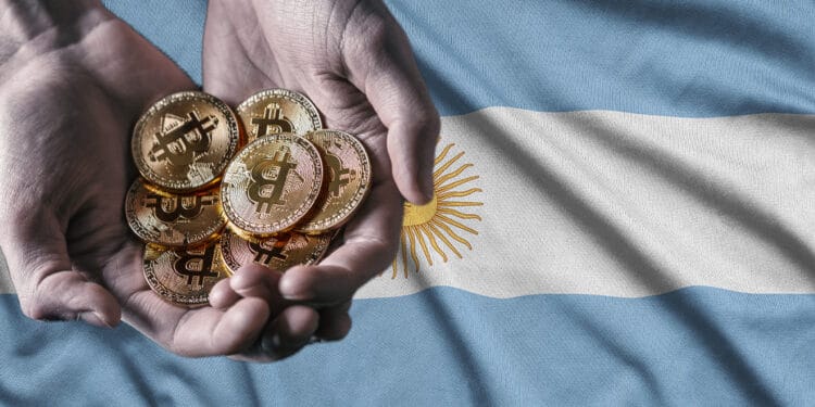 Bandera de Argentina y y mano sosteniendo bitcoins.