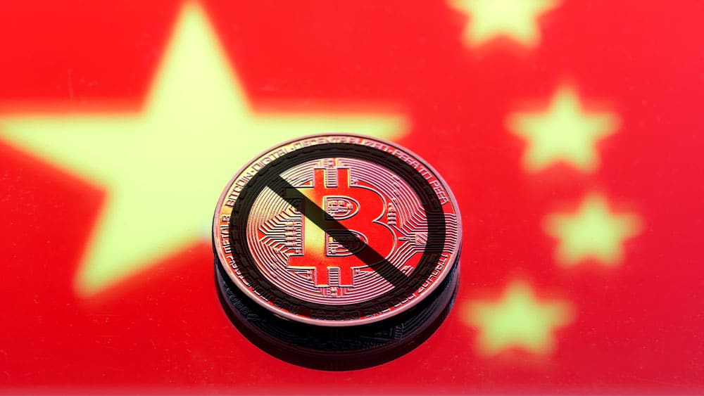 Bandera de China con bitcoin tachada como prohibida.