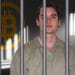 Ross Ulbricht encarcelado con logo de bitcoin en la pared.