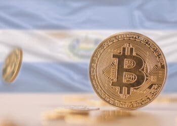 Bitcoins sobre mesa y bandera de El Salvador.