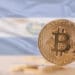 Bitcoins sobre mesa y bandera de El Salvador.