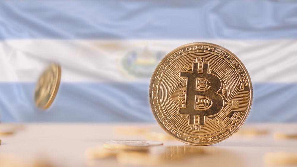 Bitcoins sobre mesa y bandera de El Salvador.