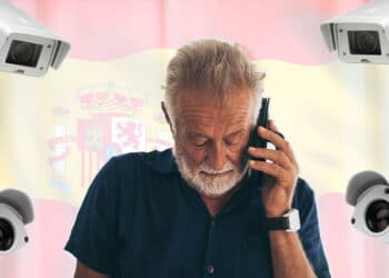 Hombre habla por teléfono con bandera de España y cámaras de vigilancia.