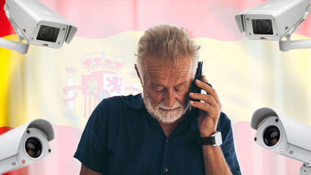 Hombre habla por teléfono con bandera de España y cámaras de vigilancia.