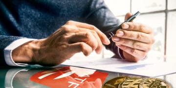 Las manos de un hombre sosteniendo un lapiz mientras lee una guía sobre un escritorio con el logo del GAFI.