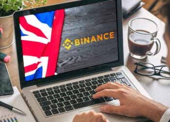 Laptop con logo de Binance y bandera de Reino Unido.