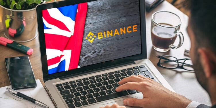 Laptop con logo de Binance y bandera de Reino Unido.