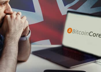 Pantalla con logo de Bitcoin Core, bandera de Reino Unido y hombre preocupado.