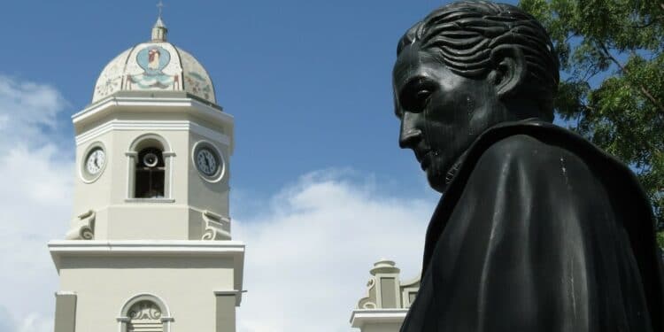 Busto de Simón Bolívar con campanario detrás.