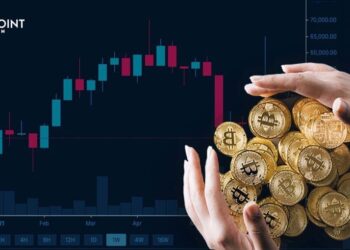 Puñado de monedas Bitcoins entre manos sobre grafica de precio