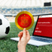 Campo de fútbol y balón con fan token de la selección de españa y su pantalla en Bitci.com.