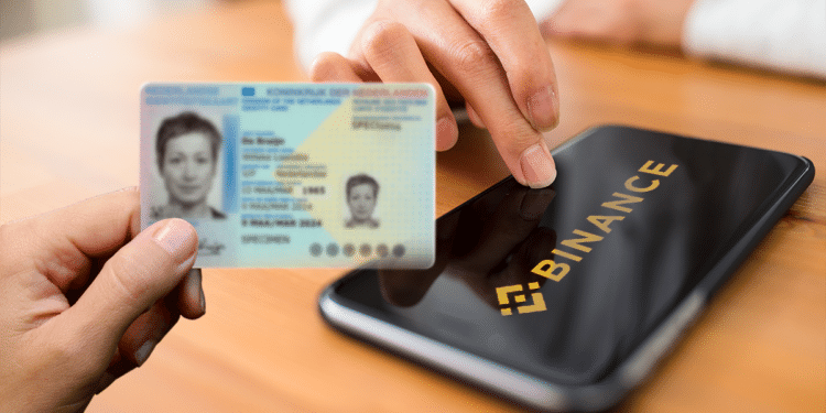 Teléfono con logo de Binance y mano sosteniendo identificación personal.