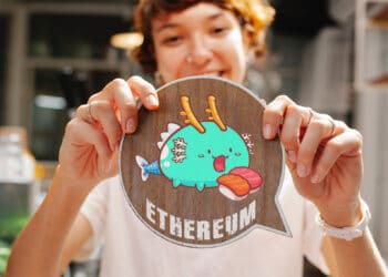 Persona sosteniendo token de axie con letras ethereum.