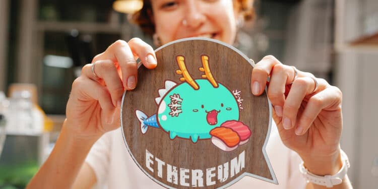 Persona sosteniendo token de axie con letras ethereum.
