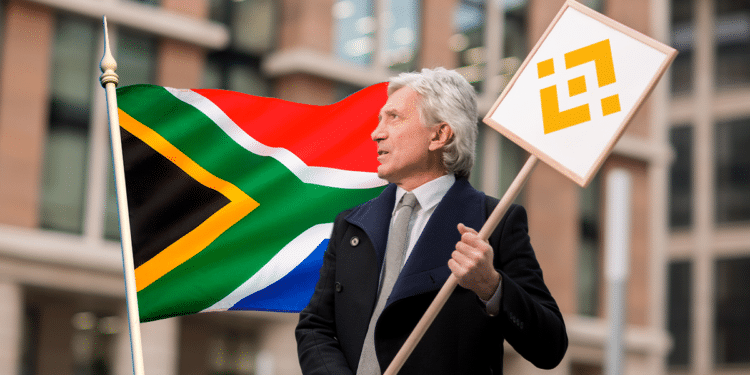 Señor con cartel de Binance y bandera de Sudáfrica.