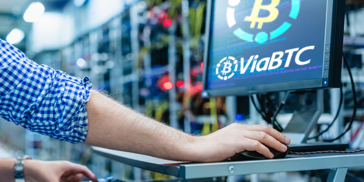 Persona en granja de BTC frente a pantalla con logo de ViaBTC.
