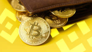 Billetera marrรณn con monedas de bitcoin sobre el logo de Binance