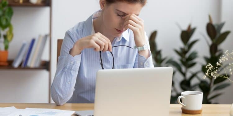 Mujer pensativa frente a una laptop
