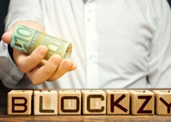 Logo de Blockzy en cubos de madera con hombre entregando billetes de euro con logo de Bitinka en camisa. Composición por CriptoNoticias. BitInka / bitinka.com; Blockzy / blockzy.com; twenty20photos / elements.envato.com.