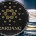 Moneda de Cardano recostada en dos pilas de criptomonedas