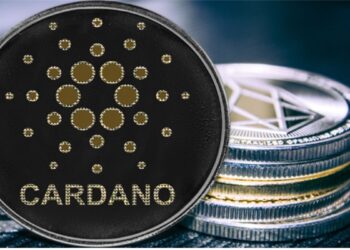 Moneda de Cardano recostada en dos pilas de criptomonedas