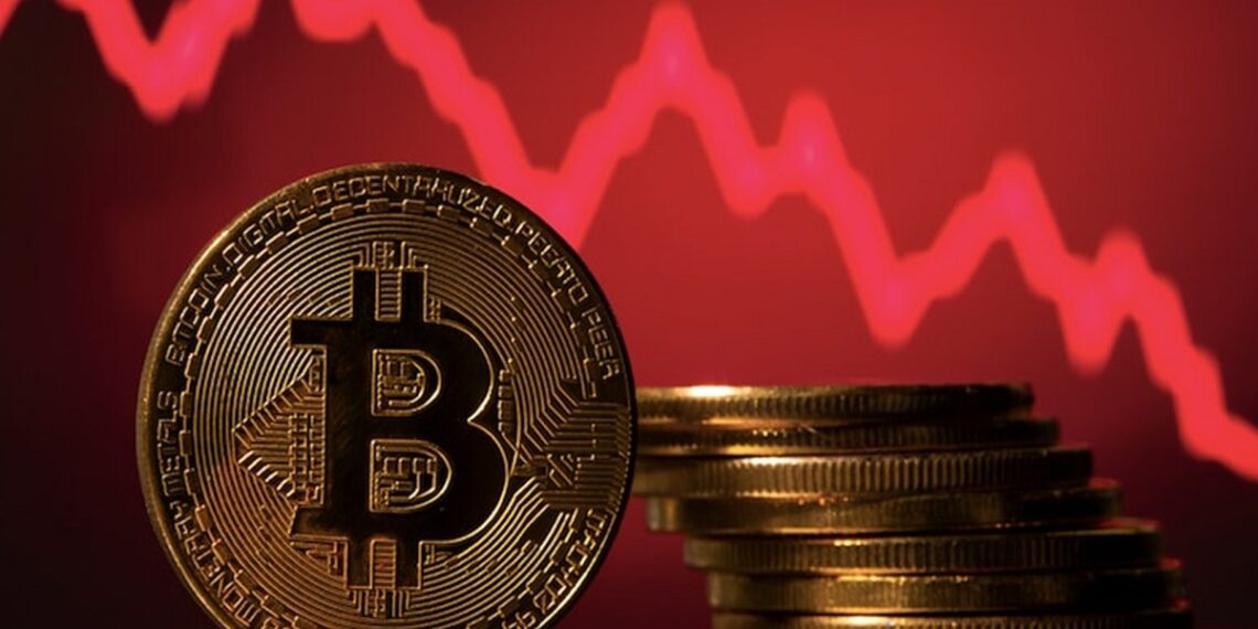 Pila de monedas de bitcoin frente a gráfico de precios en rojo