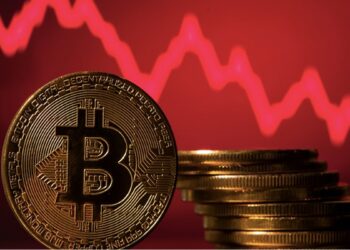 Pila de monedas de bitcoin frente a gráfico de precios en rojo