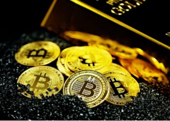 Monedas de bitcoin sobre fragmentos de carbón y al lado de un lingote