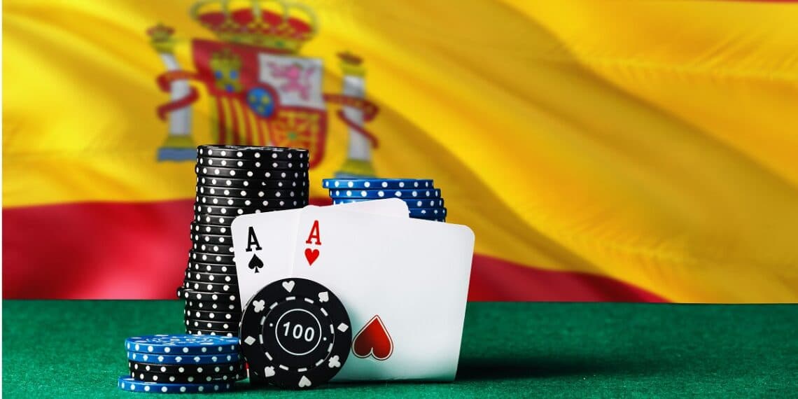 Dos ases de poker sostenidos por fichas de apuestas frente a la bandera de España.