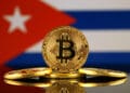 Una versión física de Bitcoin (moneda virtual) y una bandera de Cuba