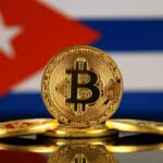 Una versión física de Bitcoin (moneda virtual) y una bandera de Cuba