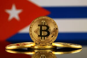Una versión física de Bitcoin (moneda virtual) y una bandera de Cuba