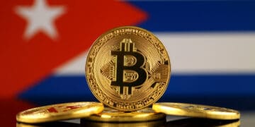Una versión física de Bitcoin (moneda virtual) y una bandera de Cuba