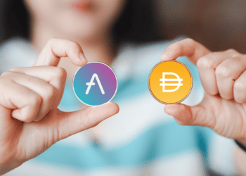 Manos sosteniendo dos criptomonedas, Aave y DAI.