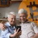 Adultos mayores mirando el celular con un bitcoin de fondo.