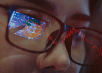Persona observando análisis de precio de Bitcoin en rojo.