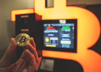Cajero o ATM de Bitcoin con mano sosteniendo la criptomoneda.