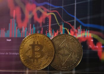 monedas de bitcoin y ether con gráfico descendente en el fondo