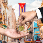 Una persona entrega una moneda física de bitcoin a otra persona y al fondo se observa una bandera de Cuba