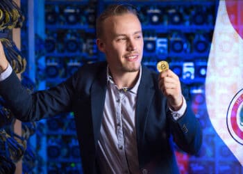 hombre sostiene moneda de bitcoin apoyado en mineros junto a bandera de paraguay