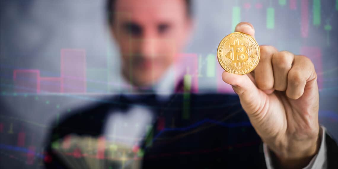 millonario sostiene moneda de bitcoin a través de gráfico de mercado