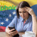 Mujer preocupada con su celular acompañada de la bandera de Venezuela y el logo de Uphold.