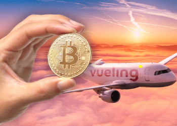 Avión con logo de Vueling y mano sosteniendo bitcoin.